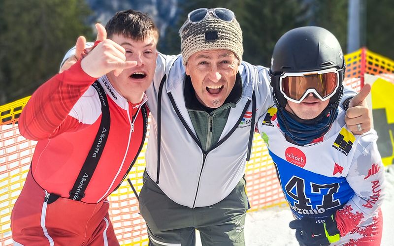  SV Caps-Obmann Robert Allgäuer inmitten der Ski-Asse Richard Strohhäusl und Markus Grameiser legt die Arme über die Schultern der erfolgreichen Sportler. Alle drei lachen in die Kamera. 