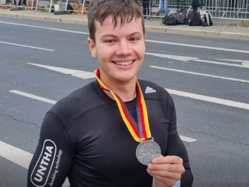 Ludwig Malter hält seine Berlin Marathon-Medaille in die Kamera und lächelt. 